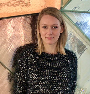 An image of a woman with blonde hair in front of a copper and mirrored wall.